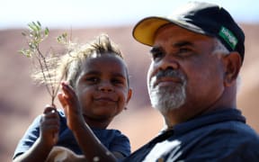 Traditional Aboriginal owners of Uluru-Kata-Tjuta, the Anangu, gather in front of the Uluru, also known as Ayers rock, after a permanent ban on climbing Uluru at the Uluru-Kata Tjuta National Park in Australia's Northern Territory on October 26, 2019.