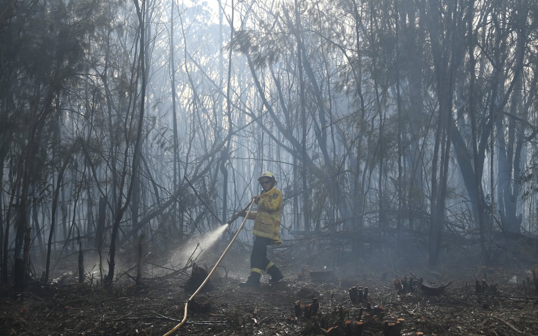 A firefighter dowses a bushfire in the residential area of Sydney (file photo). Firefighters will carry out backburning today to control two massive blazes on two sides of Sydney.