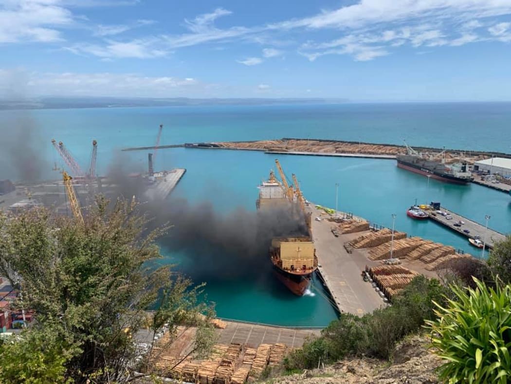 The thick black smoke clouds billowing from the ship at Napier Port draws a stark contrast with the clear blue day.