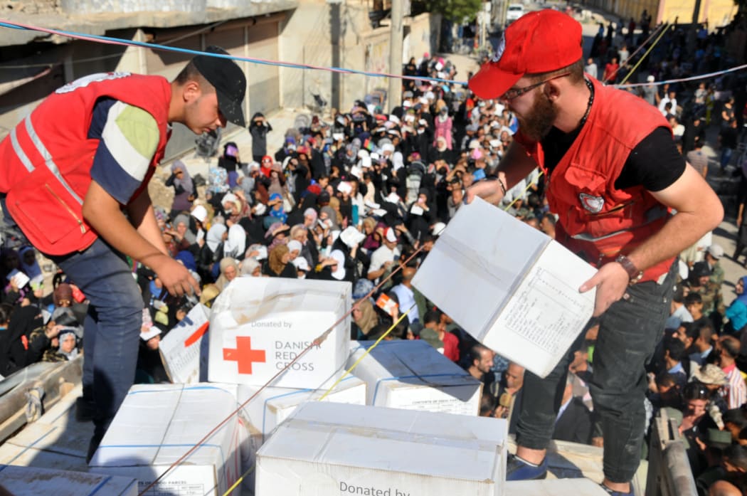 Members of the Syrian Red Crescent distribute humanitarian aid parcels to local residents in the northeastern city of Deir Ezzor on September 9, 2017.