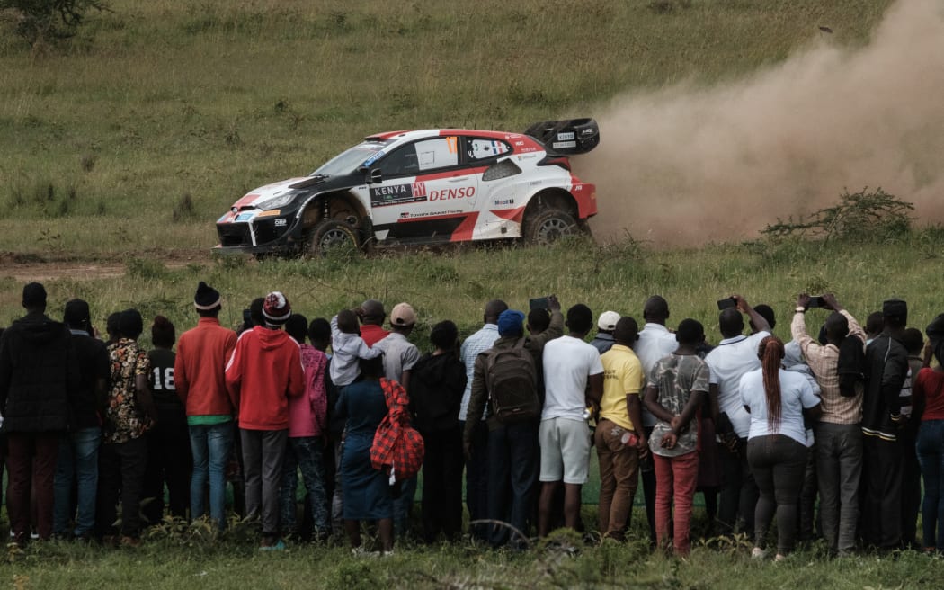 People watch Toyota GR Yaris Rally1 Hybrid steered by France's Sebastien Ogier and co-driver France's Vincent Landais during the WRC Safari Rally Kenya, part of the FIA World Rally Championship, in Nakuru, Kenya, on June 24, 2023. (Photo by Yasuyoshi CHIBA / AFP)