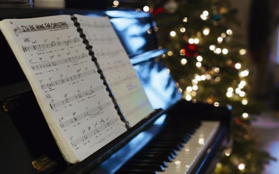 Sheet music on piano, Christmas tree in background (Photo by Adam C Bartlett / Image Source / Image Source via AFP)