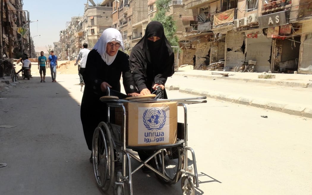 Residents of the Yarmuk Palestinian refugee camp, south of Damascus, with food distributed by the UN earlier in July.