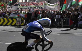 Pro-Palestinians protesters wave Palestinian flags as Team Israel Premier Tech's Israeli rider Nadav Raisberg competes during the 18th stage of the Vuelta a Espana in Spain, 11 September 2025. (Photo by Miguel RIOPA / AFP)