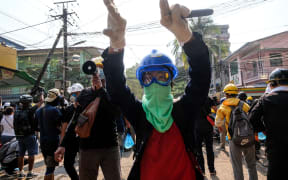A protester gestures hand to move aside on path for protesters to run  during the riot force crackdown during an anti-coup protest in Yangon, yesterday.