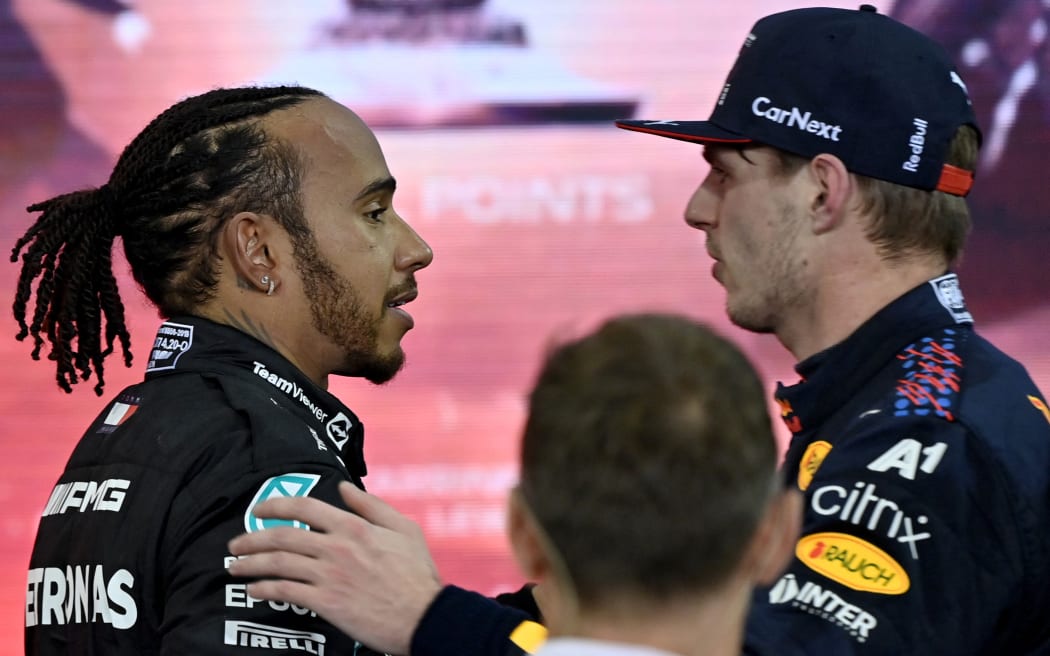 Champion Red Bull's Dutch driver Max Verstappen (right) greets second-placed Mercedes' British driver Lewis Hamilton after the Abu Dhabi F1 Grand Prix at the Yas Marina Circuit on 12 December, 2021.