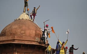 Protesters climb on a dome at the ramparts of the Red Fort as farmers demonstrate against the central government's recent agricultural reforms in New Delhi on January 26, 2021.