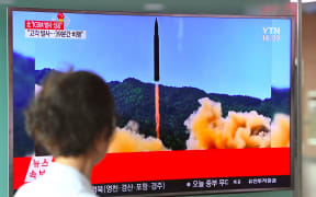 A woman walks past a television screen in the South Korean capital Seoul showing a picture of North Korea's launch of an intercontinental ballistic missile.