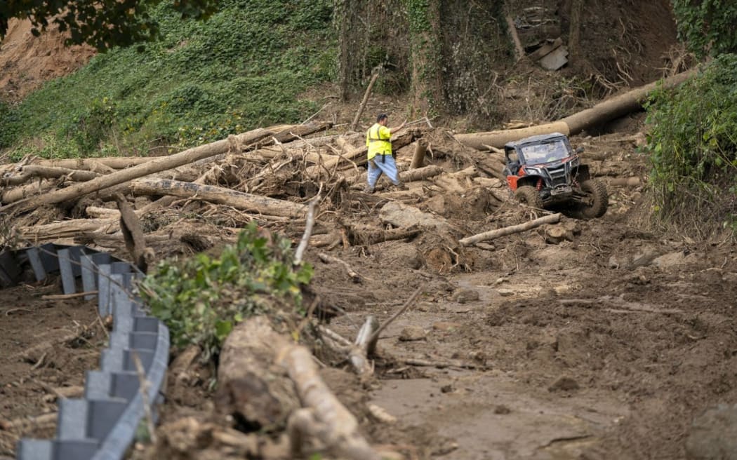 BAT CAVE, NORTH CAROLINA - OCTOBER 1: Men cut a path through a landslide on North Carolina Route 9 in the aftermath of Hurricane Helene on October 1, 2024 near Bat Cave, North Carolina. The death toll has topped 140 people across the southeastern U.S. due to the storm, according to published reports, which made landfall as a category 4 storm on Thursday. Millions are without power and the federal government has declared major disasters in areas of North Carolina, Florida, South Carolina, Tennessee, Georgia, Virginia and Alabama, freeing up federal emergency management money and resources for those states, according to the reports.   Sean Rayford/Getty Images/AFP (Photo by Sean Rayford / GETTY IMAGES NORTH AMERICA / Getty Images via AFP)
