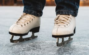 A young girl standing in skates on a frozen pond on ice. Beautiful winter day, nice blurred background.