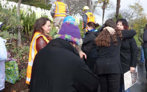 Tracey Keane-Harvey (right, holding placard) is hugged by a supporter at a workplace safety vigil in Nelson.