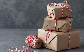 Christmas gift or present boxes wrapped in kraft paper with striped baker's twine string on textured stone background, copy space