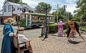 A portrait of Tram 24 running on the tracks. People standing to the side are dressed in period costume.
