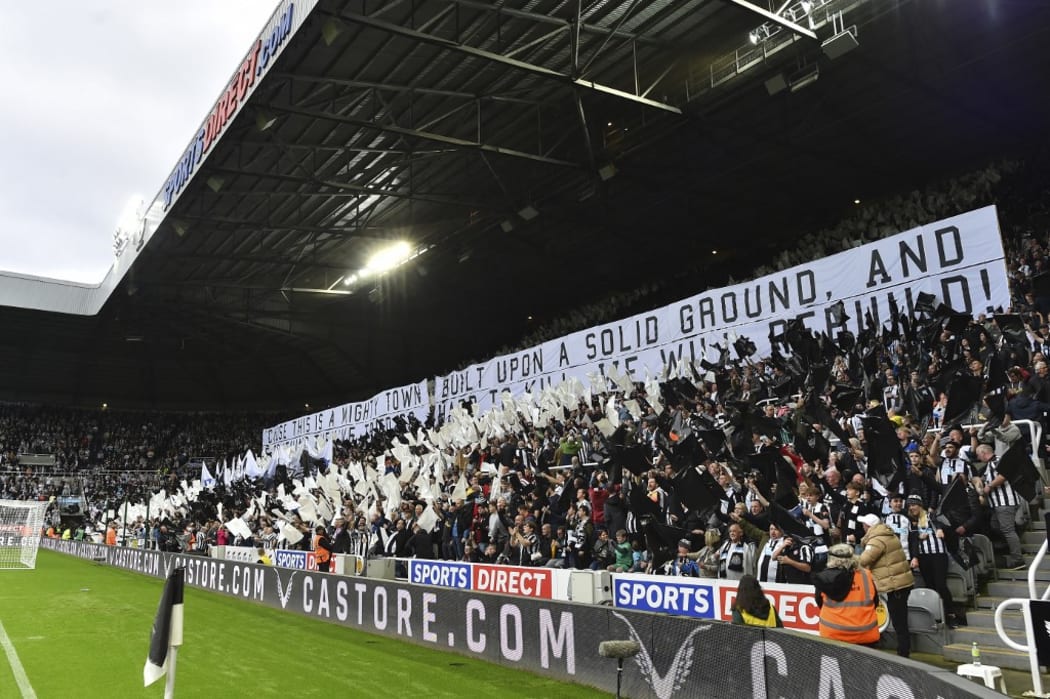 Newcastle United fans wave black and white flags and banners celebrating the club's recent take over by a Saudi-led consortium.