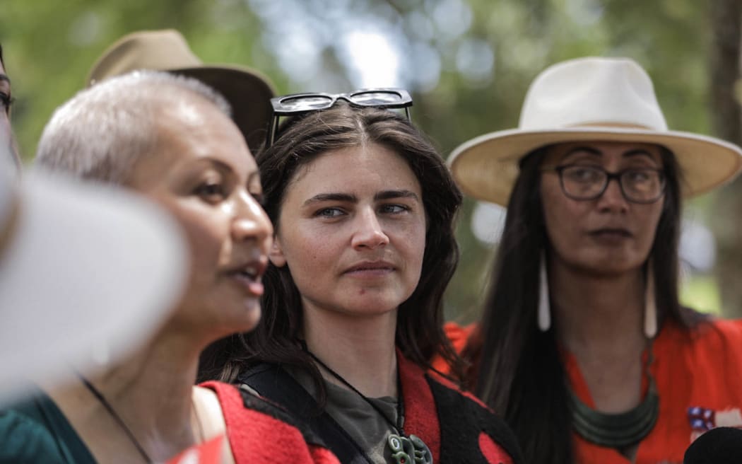 Chloe Swarbrick watches on as Marama Davidson speaks to media at Waitangi