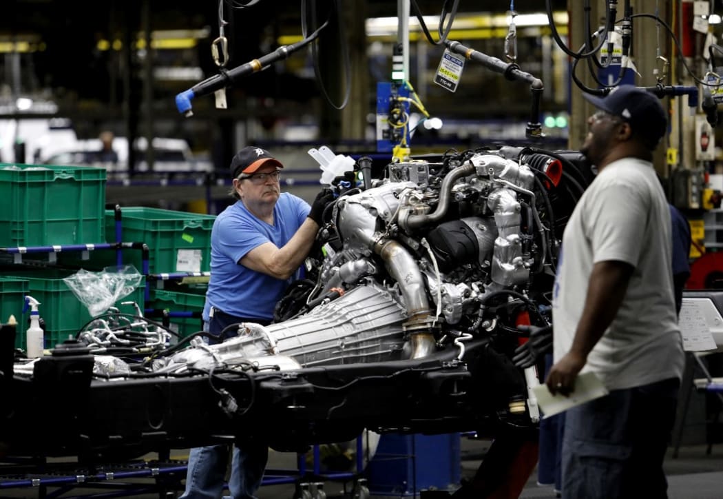 Line workers work on the chassis of full-size General Motors pickup trucks at the Flint Assembly plant on June 12, 2019 in Flint, Michigan.
