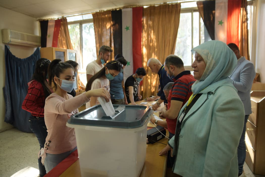 A Syrian woman casts her vote at a polling station in Aleppo on May 26, 2021.