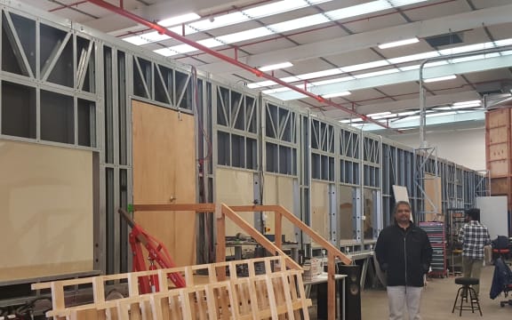 Aerodynamics researcher Rajnish Sharma stands beside the 20-metre long boundary layer wind tunnel at the University of Auckland. The wooden structure to the right is a smaller vertical wind tunnel.
