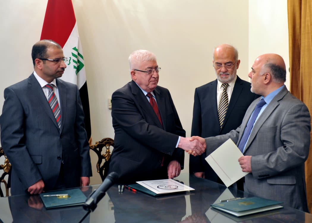Iraqi President Fuad Masum (2nd left) shakes hands with Haidar al-Abadi (r) during a brief ceremony broadcast on state television.