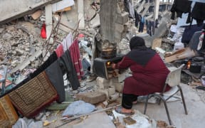 A Palestinian woman cooks food in a makeshift stove on the rubble of a building where her family took shelter in Beit Lahia in the northern Gaza Strip, ahead of the iftar fast-breaking meal during the Muslim holy month of Ramadan on March 9, 2025. Israel's energy minister said on March 9 he had given instructions to stop supplying electricity to Gaza, a week after Israel blocked all aid into the war-ravaged Palestinian territory. (Photo by Omar AL-QATTAA / AFP)