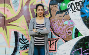 Portrait of Regina Tito standing against a wall
