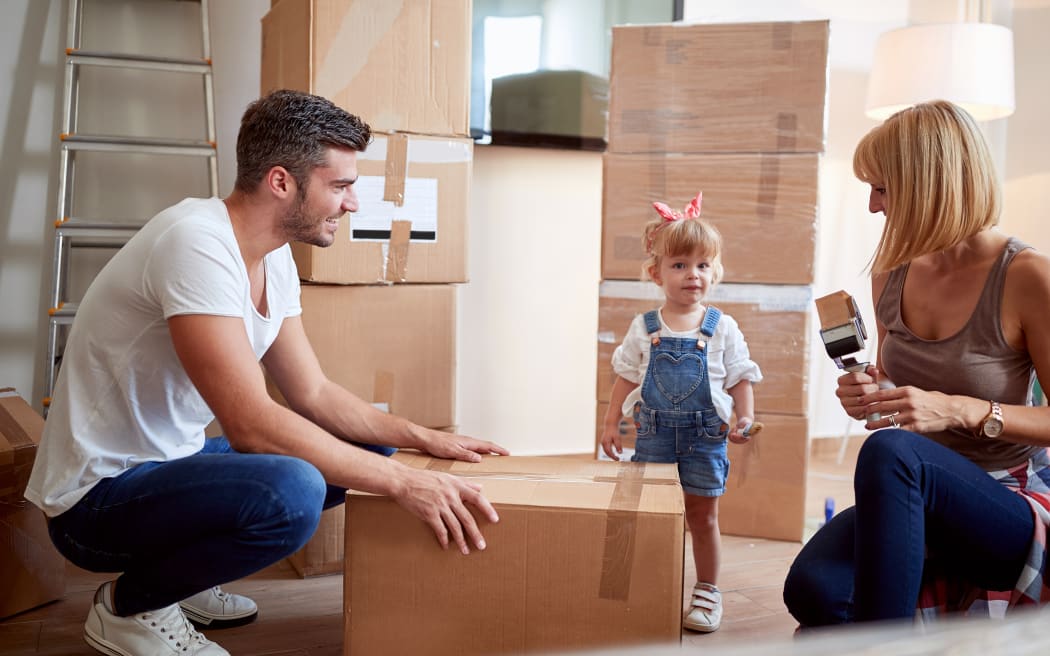 Parents packing boxes with preschool child in an apartment to move houses.