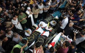 Palestinian mourners carry the bodies of victims killed in an Israeli air strike, during their funeral in Gaza City, on 5 August, 2022. A senior militant and a young girl were among those killed.
