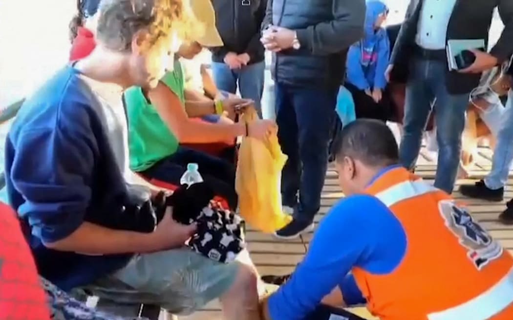 An image grab taken from a video made available by Egypt's Red sea governor’s office on November 25, 2024 shows rescue workers helping tourists and crew members after a diving boat capsized in the Red Sea off Egypt's coast. - Rescuers recovered four bodies and three survivors on November 26, a day after a a boat capsized off of Egypt's eastern coast, according to Red Sea governor Amr Hanafi, with nine people still missing. (Photo by Red Sea governor’s office / AFP) / RESTRICTED TO EDITORIAL USE - MANDATORY CREDIT "AFP PHOTO / RED SEA GOVERNOR'S OFFICE " - NO MARKETING NO ADVERTISING CAMPAIGNS - DISTRIBUTED AS A SERVICE TO CLIENTS