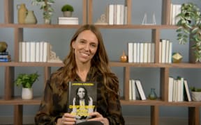 Jacinda Ardern holds a copy of her memoir, A Different Kind of Power.