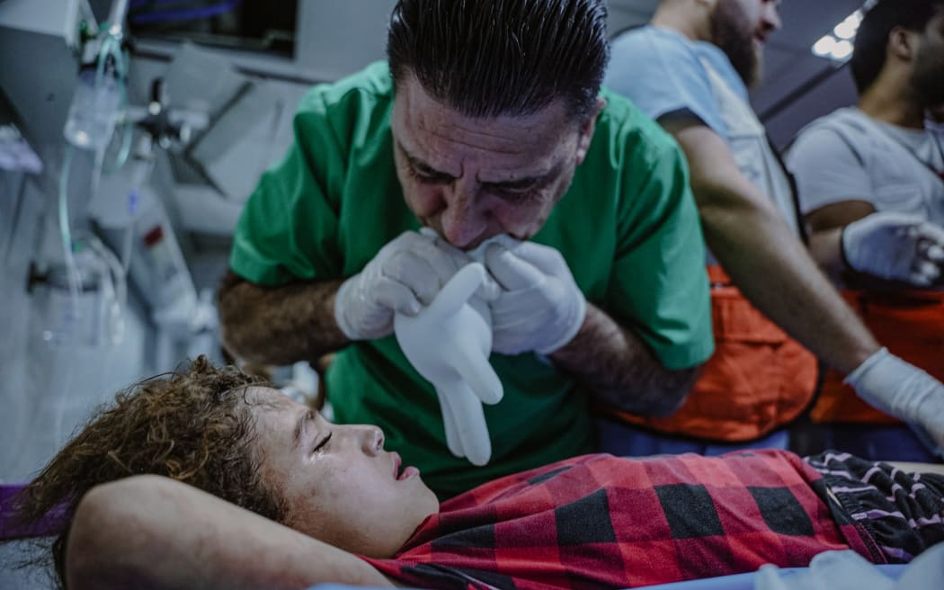 Several children and women sustained injuries due to an Israeli airstrike that targeted a residential house in the Al-Amal neighborhood, located to the west of Khan Yunis city. A Red Crescent doctor Hilal Ahmar is seen trying to help an injured girl in the hospital on 22 October, 2023. (Photo by Saher Alghorra / Middle East Images / Middle East Images via AFP)