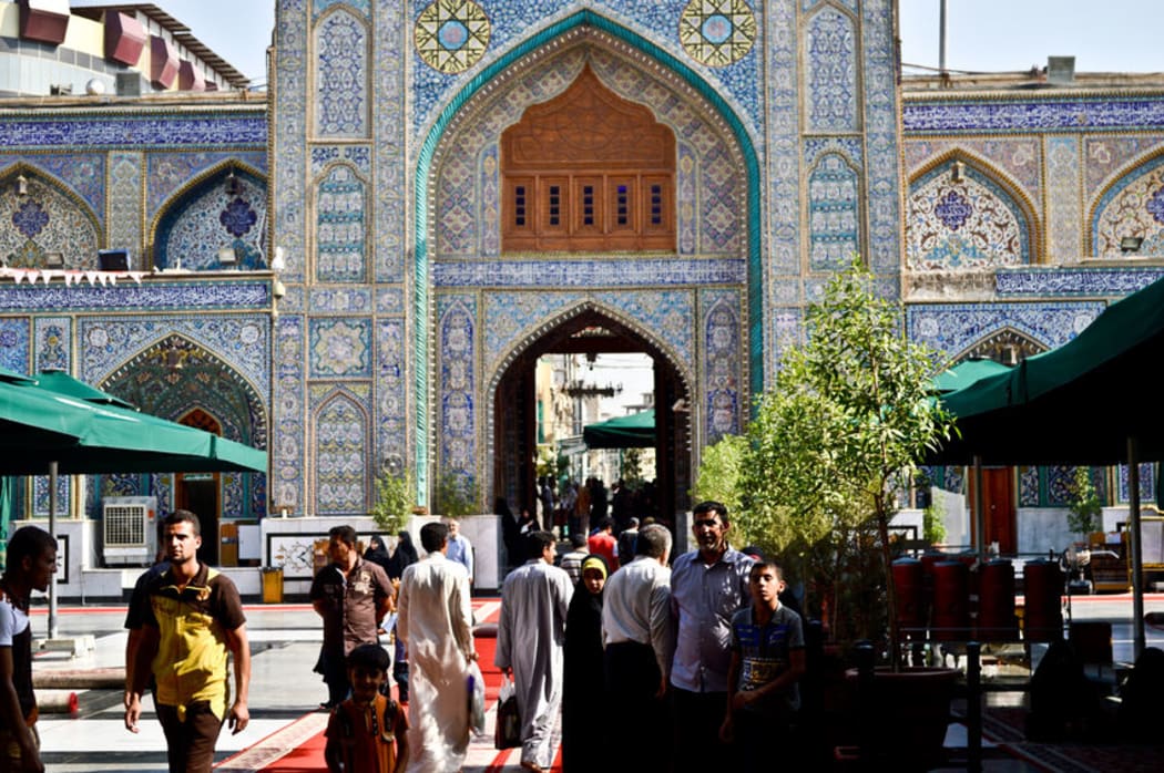 Pedestrians walk past a Shi-te shrine in Kadhimiya, Baghdad