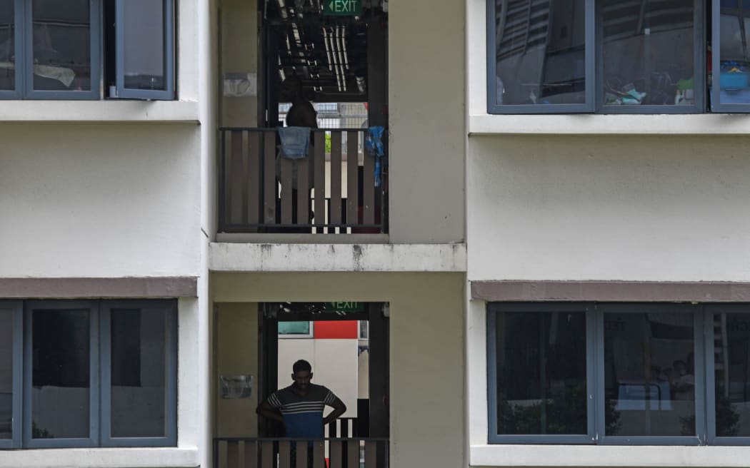 A migrant worker stands along the corridor at a foreign workers' domitory, currently under isolation as a preventive measure against the spread of the COVID-19 novel coronavirus, in Singapore on April 27, 2020. -
