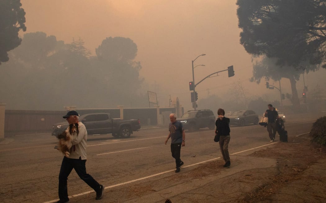 LOS ANGELES, CALIFORNIA - JANUARY 7: People evacuate along Sunset Boulevard as the Palisades Fire burns amid a powerful windstorm on January 7, 2025 in the Pacific Palisades neighborhood of Los Angeles, California. The fast-moving wildfire is threatening homes in the coastal neighborhood amid intense Santa Ana Winds and dry conditions in Southern California   Apu Gomes/Getty Images/AFP (Photo by Apu Gomes / GETTY IMAGES NORTH AMERICA / Getty Images via AFP)