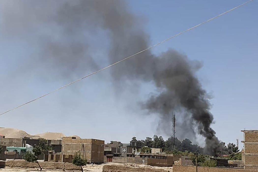 A smoke plume rises from houses amid ongoing fight between Afghan security forces and Taliban fighters in the western city of Qala-e-Naw, the capital of Badghis province, on 7 July 2021.