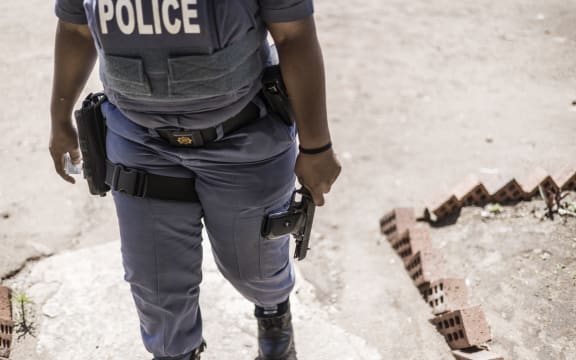 A South Africa Police Service (SAPS) officer holds a confiscated 9mm pistol at the Isulabasha Primary School at the Mistake Farm area in Umzinto, on November 1, 2021. Voters who opposed the candidate imposed by the ruling African National Congress (ANC) barricaded the road with large stones and dug a trench to prevent Electoral Commission officials to reach the voting station at the Isulabasha Primary school, de facto shutting down in protest the only voting station in the area. South African Police Services (SAPS) later reopened the road and the polling station. (Photo by MARCO LONGARI / AFP)