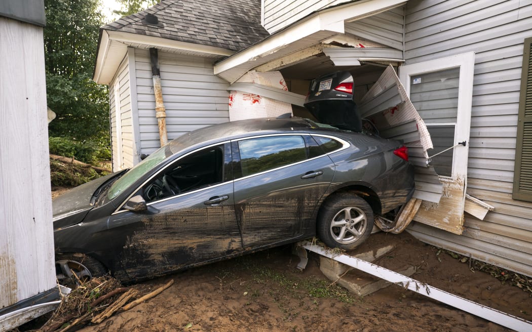 OLD FORT, NORTH CAROLINA - SEPTEMBER 30: A storm damaged car rests on a house in the aftermath of Hurricane Helene on September 30, 2024 in Old Fort, North Carolina. According to reports, at least 90 people have been killed across the southeastern U.S., and millions are without power due to the storm, which made landfall as a Category 4 hurricane on Thursday. The White House has approved disaster declarations in North Carolina, Florida, South Carolina, Tennessee, Georgia, Virginia and Alabama, freeing up federal emergency management money and resources for those states.   Sean Rayford/Getty Images/AFP (Photo by Sean Rayford / GETTY IMAGES NORTH AMERICA / Getty Images via AFP)