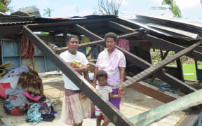 Usenia Nemai and daughters Rusila, 18, and Marie Grace, 5, stand at what used to be the lounge of their two-bedroom home in Driti village.