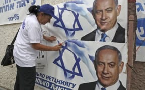A woman places electoral banners for the Likud party showing Israeli Prime Minister Benjamin Netanyahu, in the southern Israeli city of Beersheva on 15 September 2019.