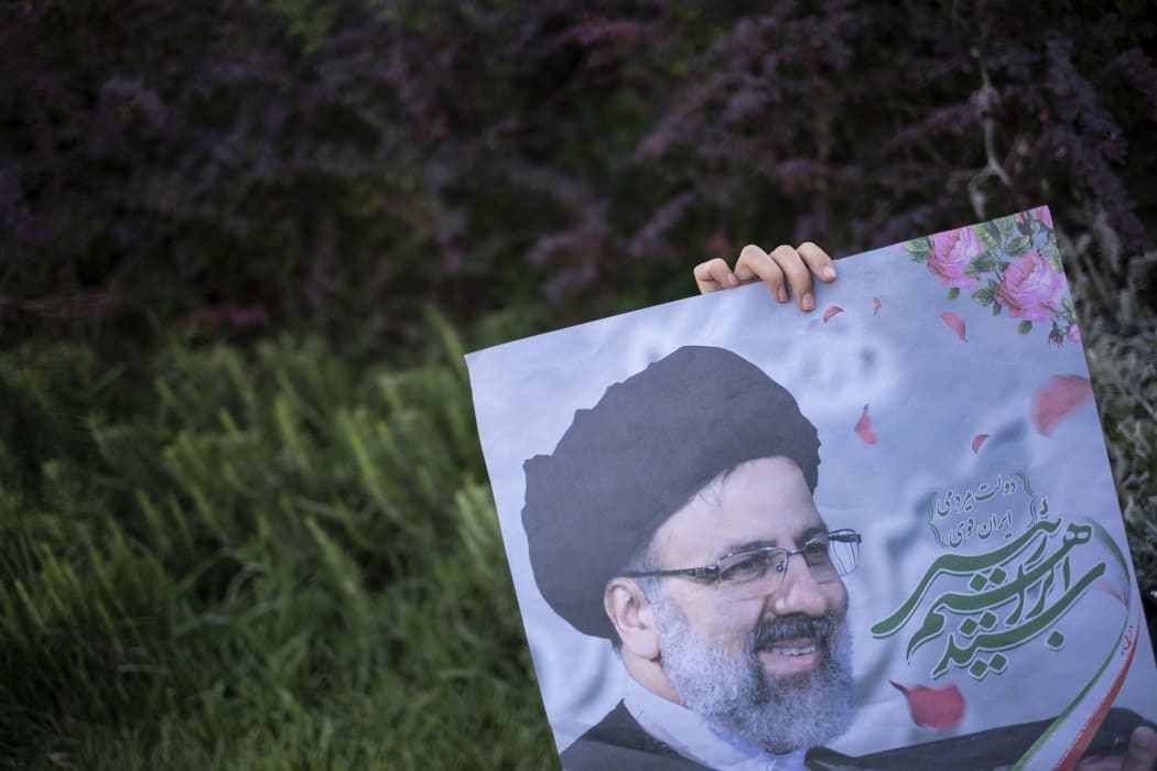 A supporter of presidential elections candidate Ebrahim Raisi holds an electoral poster for Raisi.