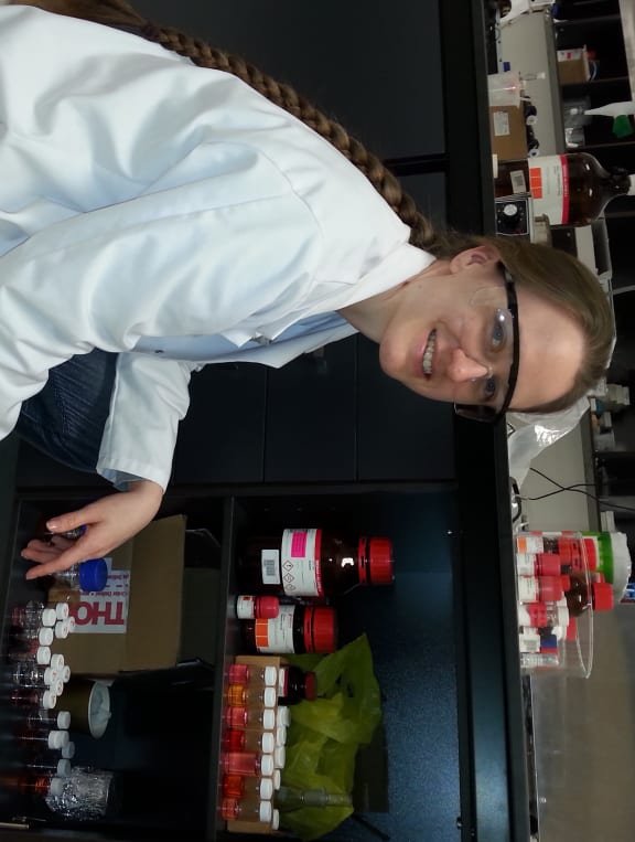Sarah Thompson in front of a cupboard of pigments in vials