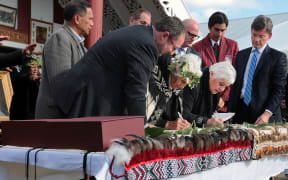 Te Tai Hauauru MP Tariana Turia (right) signs as Treaty Negotiations Minister Chris Finlayson looks on (far right).