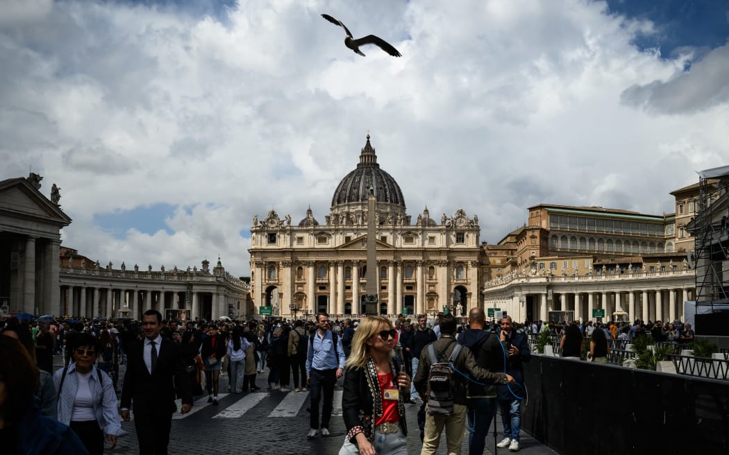A seagull flies overhead as attendees wait for the start af the conclave, near St Peter's Square, in front of St Peter's Basilica, in The Vatican, on May 7, 2025. (Photo by JEFF PACHOUD / AFP)