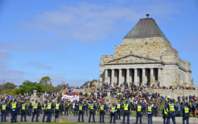 Demonstrators gather during an anti-lockdown protest and police officers stand guard in Melbourne, Australia.