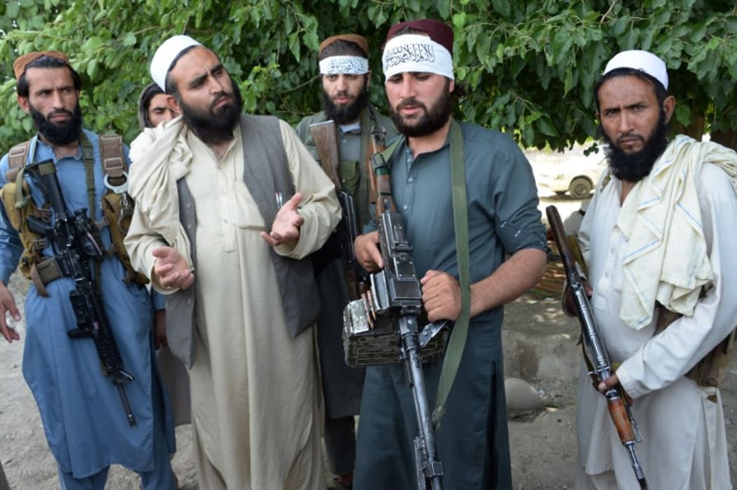 Afghan Taliban militants stand with residents as they took to the street to celebrate ceasefire on the second day of Eid in the outskirts of Jalalabad on June 16,2018. - AFP)