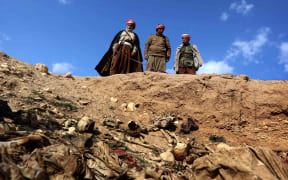 Members of the Yazidi community search for missing relatives in the remains of people killed by IS a day after Kurdish forces discovered a mass grave near the Iraqi village of Sinuni, in the northwestern Sinjar area.