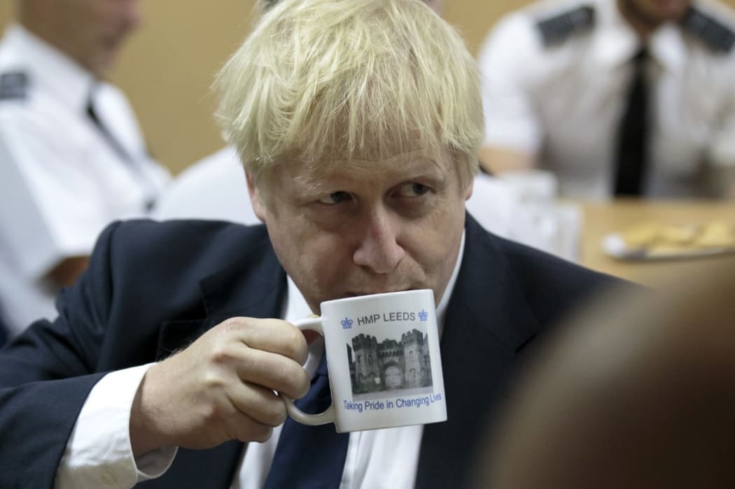 Britain's Prime Minister Boris Johnson drinks from a HMP Leeds prison mug as he talks with prison staff during a visit to HM Prison Leeds, a Category B men's prison in Leeds, northern England, on August 13, 2019. (Photo by Jon Super / POOL / AFP)