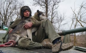 A serviceman of militia of Donetsk People's Republic (DPR) with a dog sits on an armoured vehicle outside Mariupol, Ukraine.