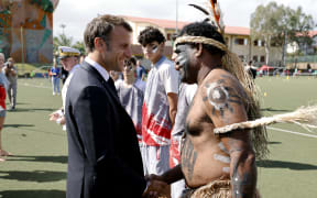 French President Emmanuel Macron shakes hands with a traditional dancer during a visit to the Magenta suburb of Noumea.