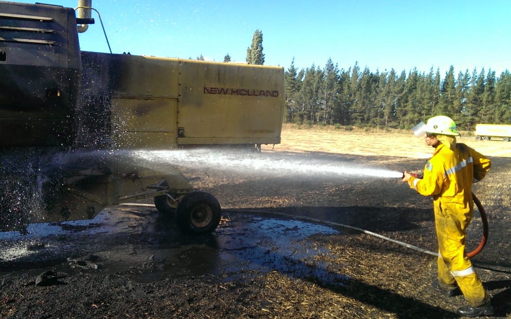 Firefighters dampen down the combine harvester on Michael Manion's farm.