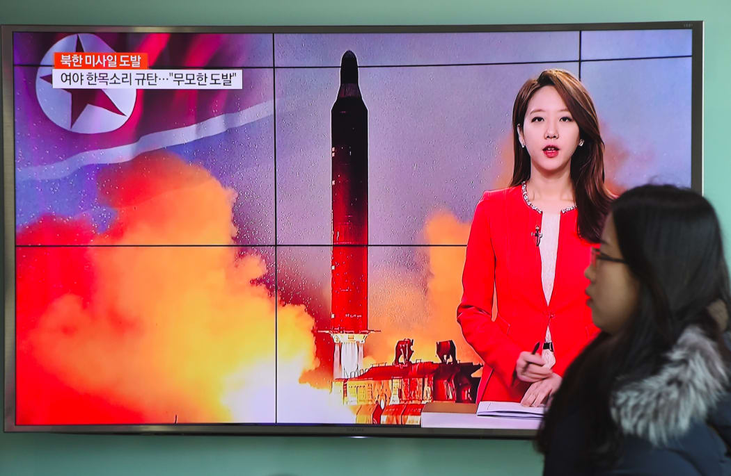 A woman walks past a television screen showing file footage of North Korea's missile launch at a railway station in Seoul on February 12, 2017.